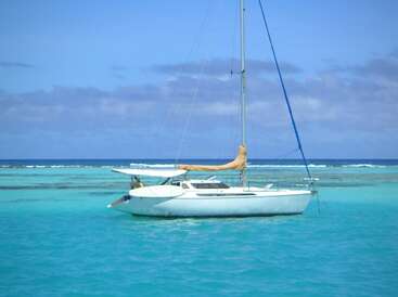 The image depicts a serene scene of a white sailboat floating in the ocean, with a vibrant blue sky and sea, evoking a sense of tranquility and relaxation.